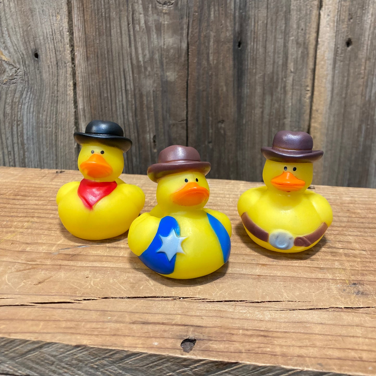 Classic yellow rubber ducks decked out in cowboy hats, bandanas and belt buckles! 

choose between 3 styles. 
Black hat, red bandana, brown hat blue vest with star badge, or brown hat with brown belt buckle.
approx. 2"x2" vinyl.