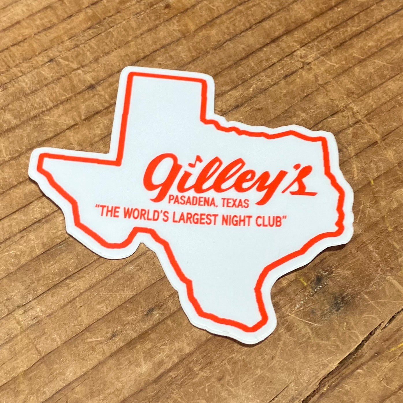 Vintage inspired Texas shaped vinyl sticker in white, outlined in red, with Gilley's Pasadena, TX "The World's Largest Night Club" logo written in red.



