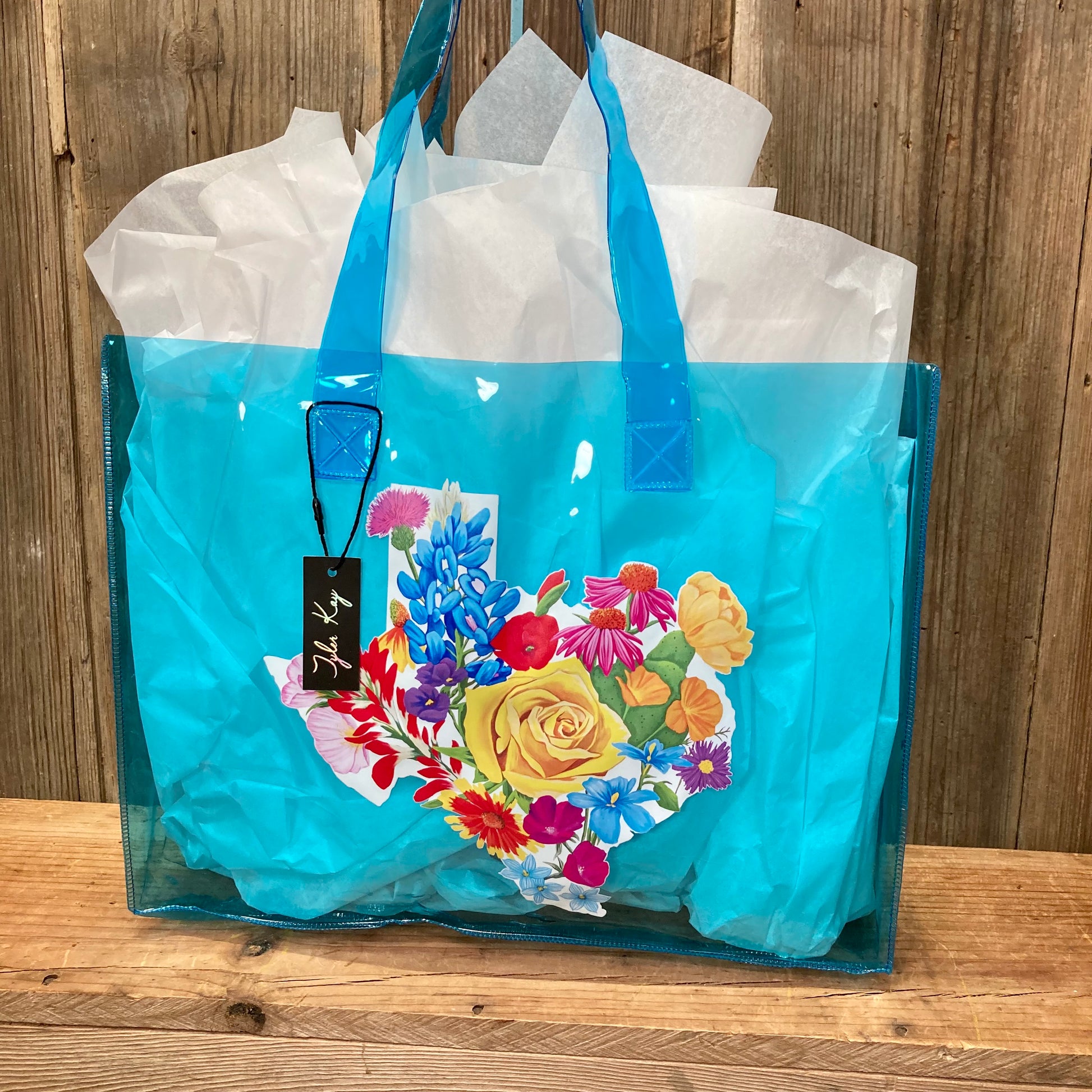 colorful jelly tote bags featuring the vibrant Texas Floral artwork by muralist Tyler Kay. Artwork is of a white Texas background covered by colorful Texas wildflowers.

choose from clear, black, blue, or white.

15.5" x 12"