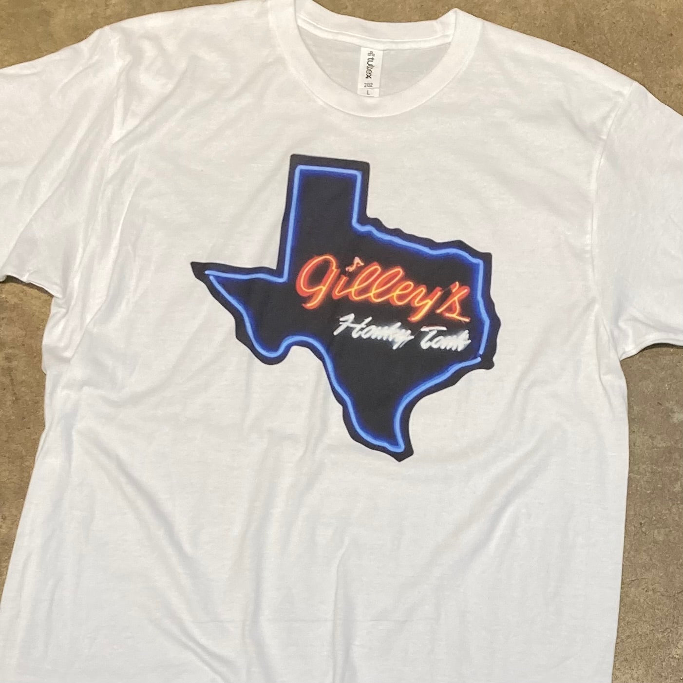 Gilley’s Honky Tonk Neon T-Shirt with a neon-style design of the Texas state, showcasing the iconic Gilley’s logo. A must-have for Gilley’s enthusiasts and Texas pride.