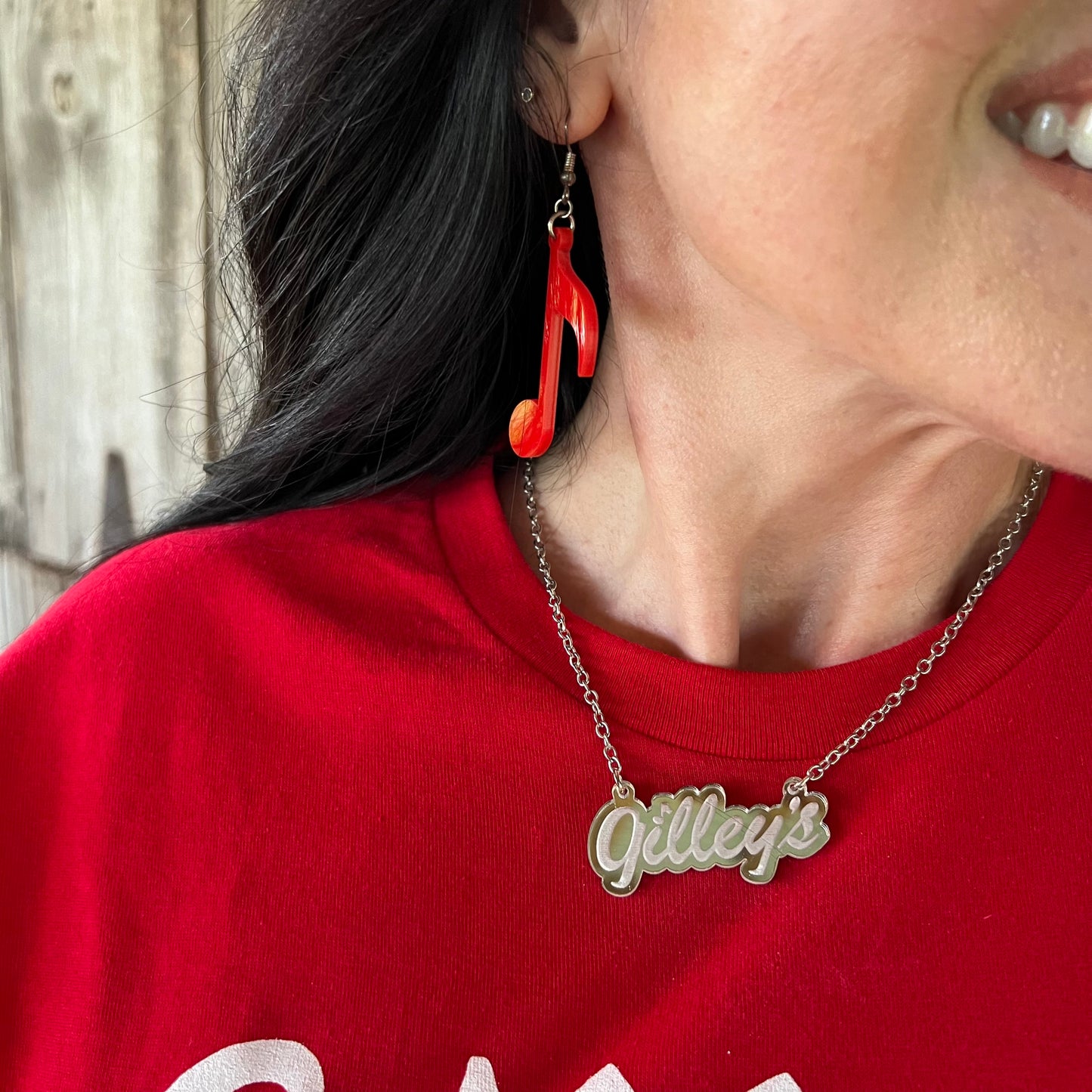 Gilley’s Logo Necklace worn on a red shirt, showing the mirrored acrylic pendant on a 16” chain. Stylish and handcrafted in Texas.