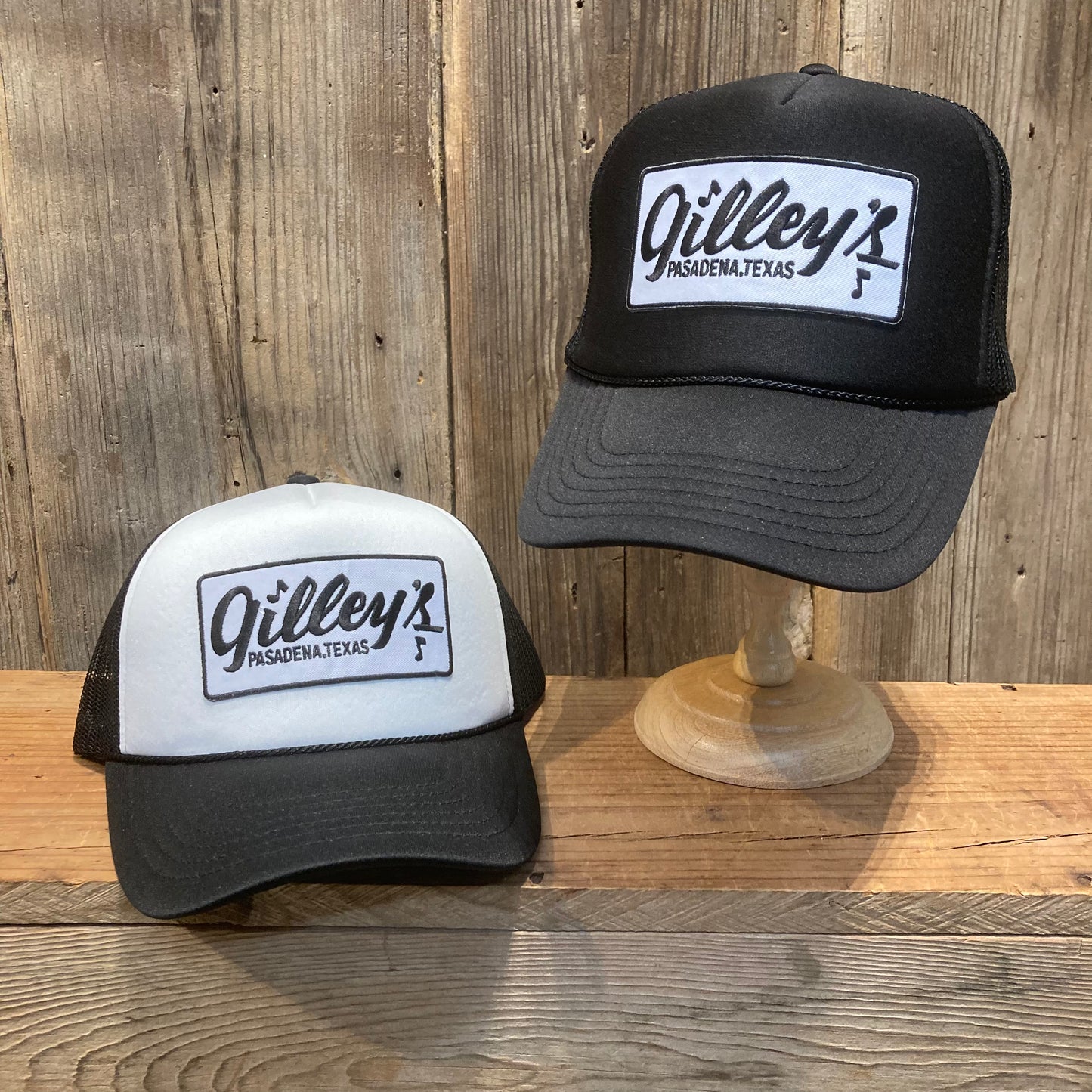 Gilley’s Pasadena, Texas black and white foam trucker hats displayed on rustic wood background