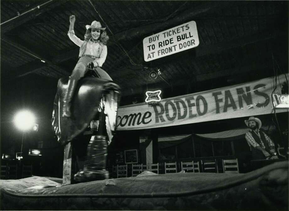 Historic black and white photo of woman riding the mechanical bull at Gilley's nightclub