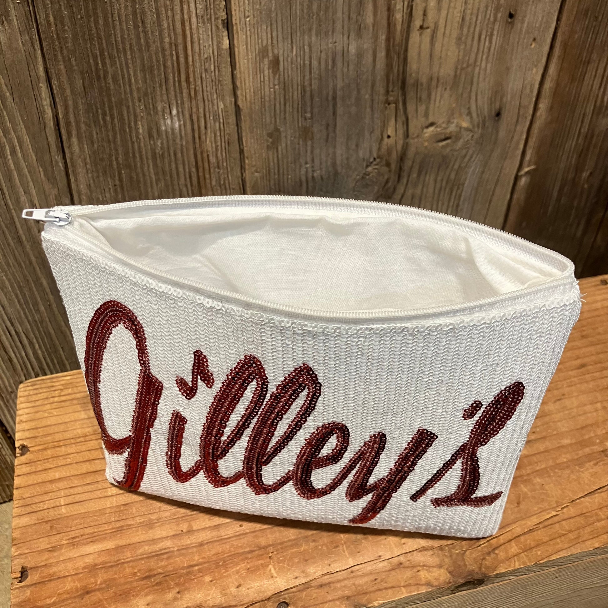 Gilley’s Sequin Makeup Bag with a sparkling red logo, showing the interior of the bag, perfect for storing cosmetics and other essentials. A stylish and functional accessory.