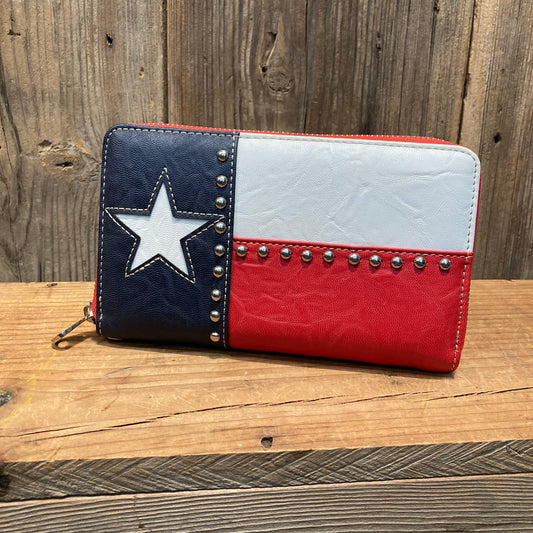 Show your Texas pride with this Lone Star flag wallet. Texas flag colors with inset white star, with silver ball beads lining the inside of the flag.

Includes wrist strap.

Man-made leather, zipper closure. 

7.75 x 4.5 x 1.5 inches 